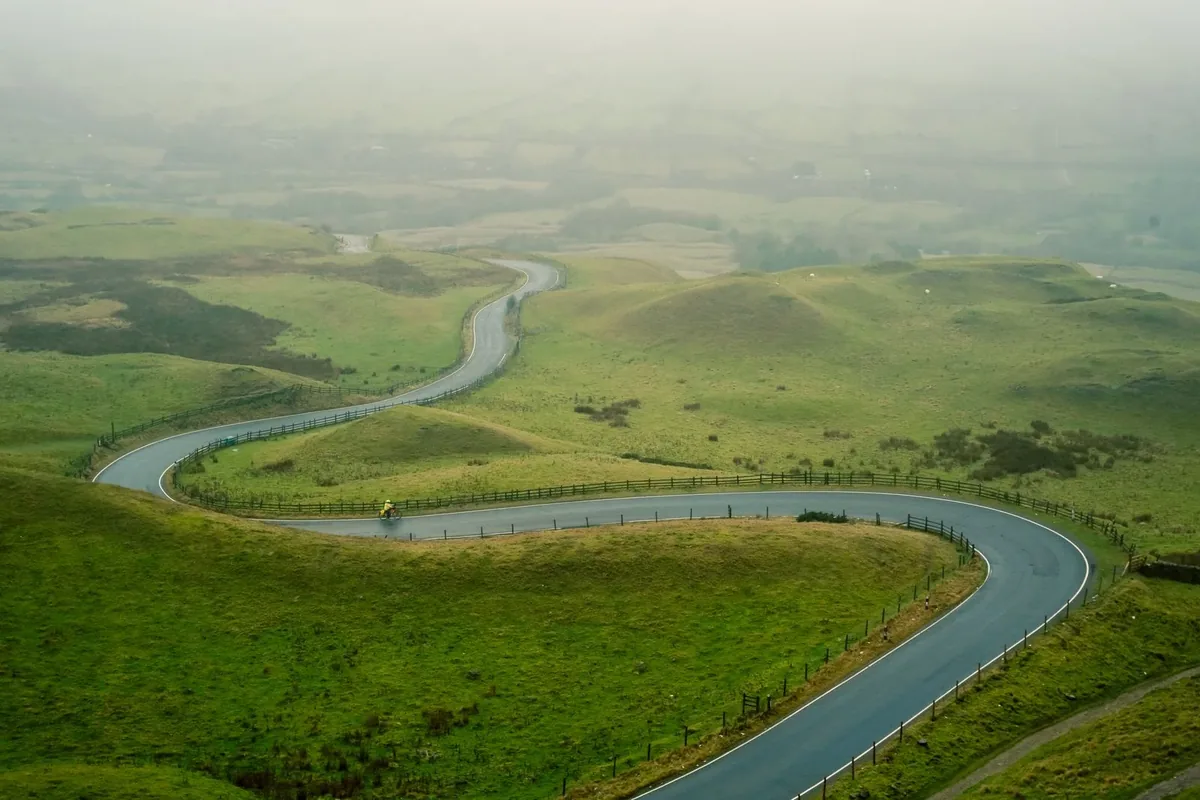 A cyclist on a road in the English countryside